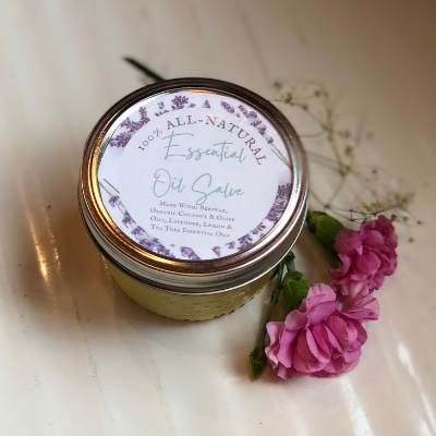 jar of 100% all-natural essential oil salve sitting on white counter with flowers surrounding