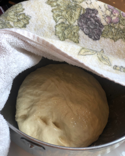 homemade white bread dough ball covered and resting to rise. 