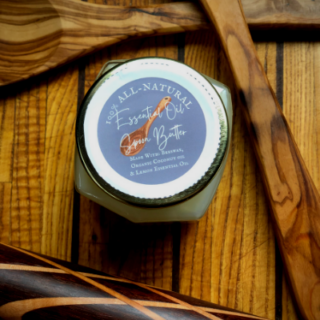 beautiful jar of spoon butter with a grey label, white lettering. Butter is framed by beautiful handmade wooden tools.