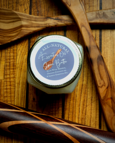 beautiful jar of spoon butter with a grey label, white lettering. Butter is framed by beautiful handmade wooden tools.